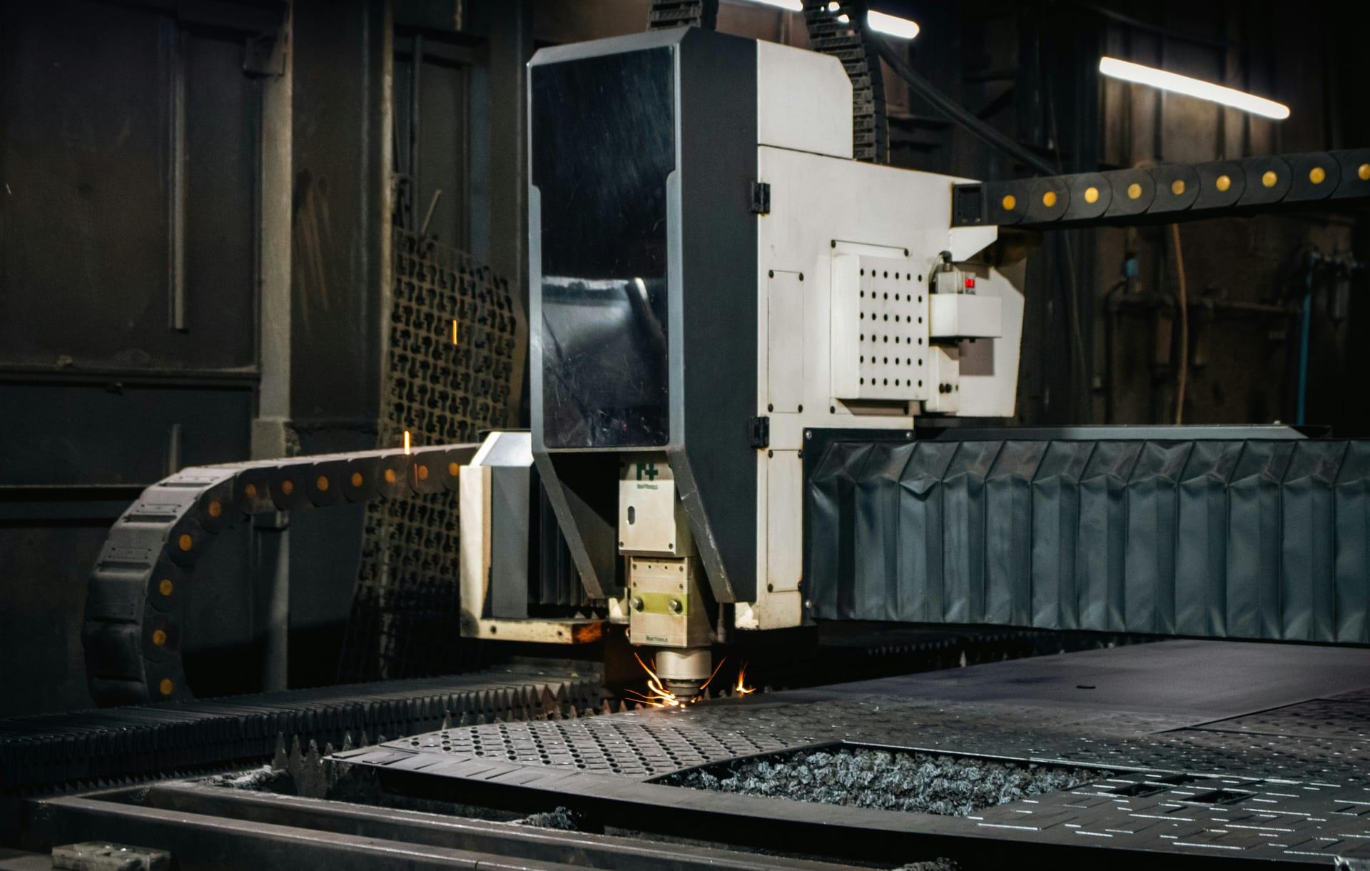 CNC laser cutting head shaping sheet metal, sparks flying on the cutting bed